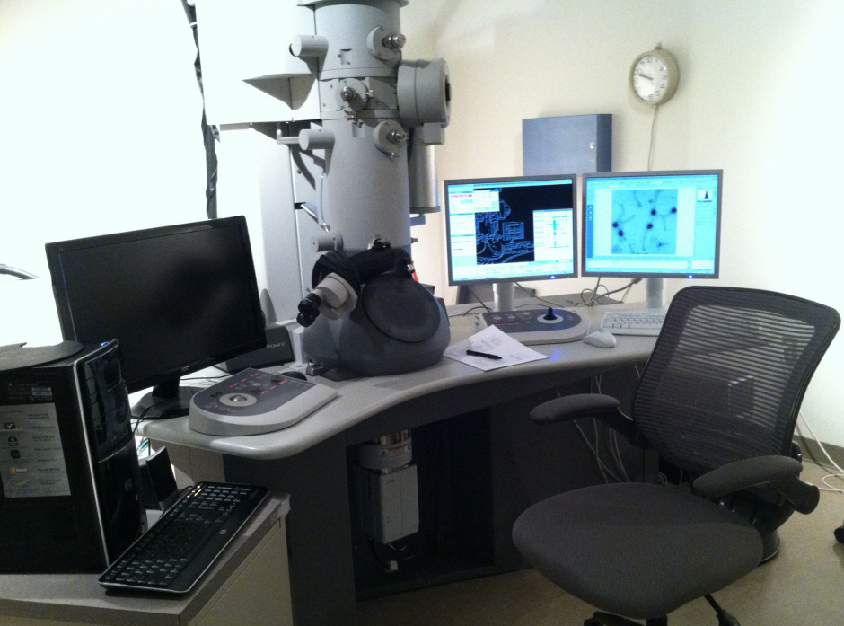 A picture of a desk with computer monitors and a transmission electron miscroscopy on top.